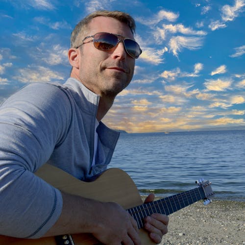 Ian holding a guitar on the beach