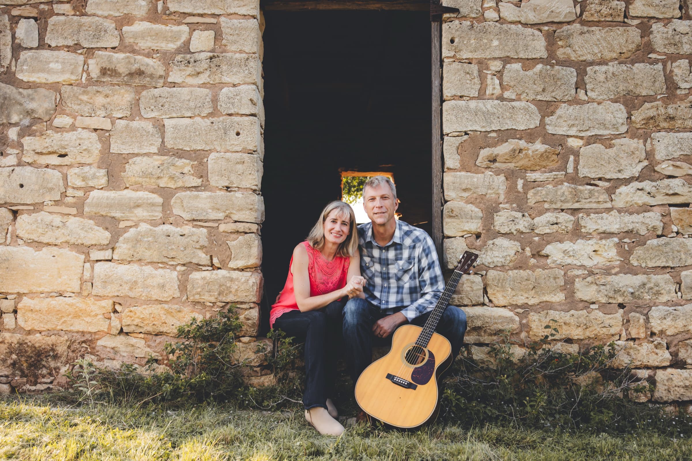 Ian and a companion sitting together in a stone doorway beside his guitar