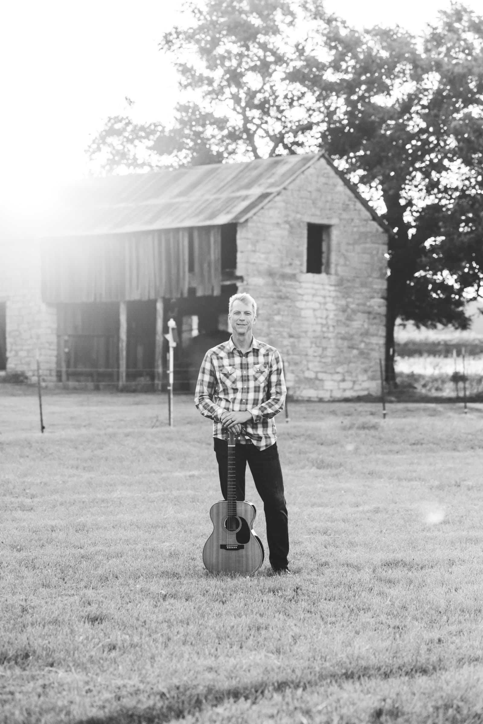 Ian standing in a field in front of a stone barn